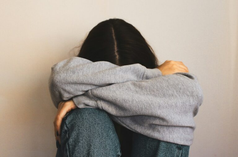 a woman sitting on the floor with her arms wrapped around her head